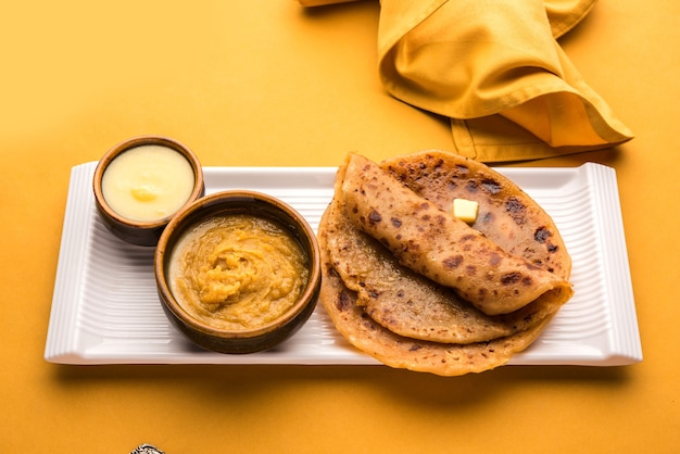 Photo puran poli, également connu sous le nom de holige, est un pain plat sucré indien consommé principalement pendant le festival holi. servi dans une assiette avec du ghee pur sur fond coloré ou en bois