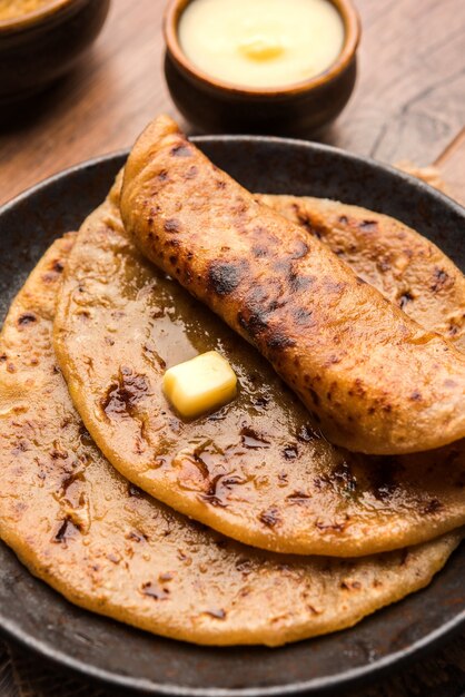 Photo puran poli, également connu sous le nom de holige, est un pain plat sucré indien consommé principalement pendant le festival holi. servi dans une assiette avec du ghee pur sur fond coloré ou en bois