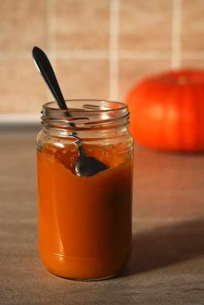 Purée de citrouille pour bébé dans un bocal en verre avec une cuillère et une citrouille fraîche