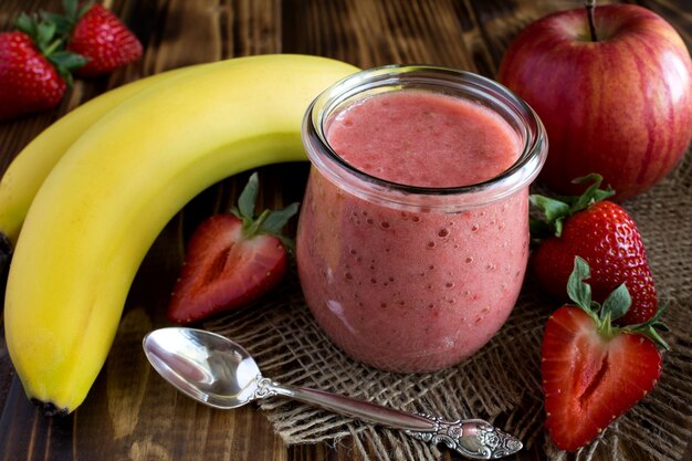 Purée de fraise, banane et pomme sur le fond en bois rustique