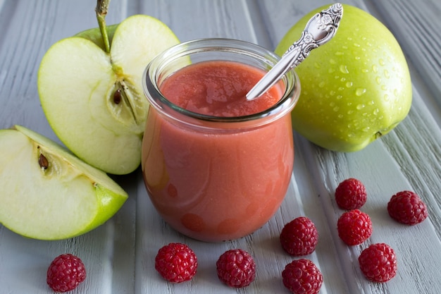 Purée de pommes et de framboises dans le bocal en verre sur la table grise