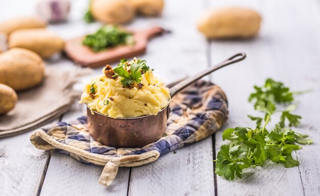 Purée de pommes de terre à l'ancienne décorée d'herbes de persil et de morceaux de bacon rôti.