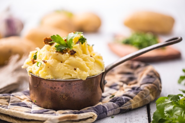 Purée de pommes de terre à l'ancienne décorée d'herbes de persil et de morceaux de bacon rôti.