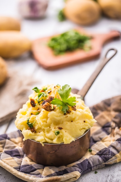 Purée de pommes de terre à l'ancienne décorée d'herbes de persil et de morceaux de bacon rôti.