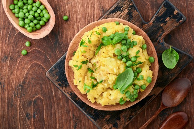 Purée de pommes de terre au beurre, petits pois, oignons, basilic sur fond de bois rustique.