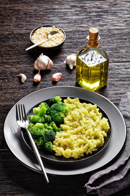 Purée de pommes de terre au brocoli saupoudrée d'amandes hachées servie avec des fleurons de brocoli cuits à la vapeur sur une plaque noire sur une table en bois sombre