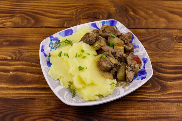 Purée de pommes de terre au foie de poulet cuit avec pomme et oignon sur table en bois