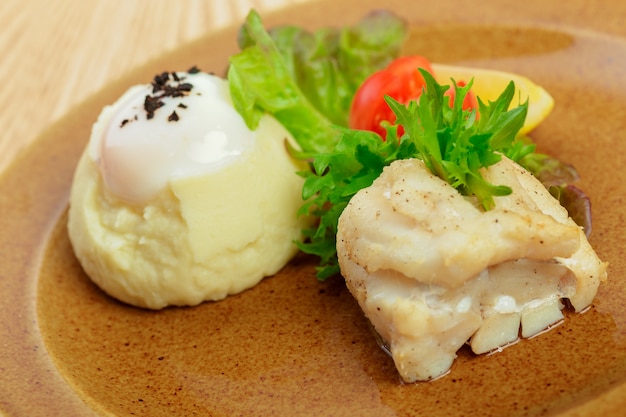 Purée de pommes de terre au jaune d'œuf et une tranche de poisson