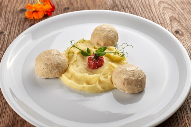 Purée de pommes de terre avec des boulettes de viande à la vapeur sur une plaque blanche