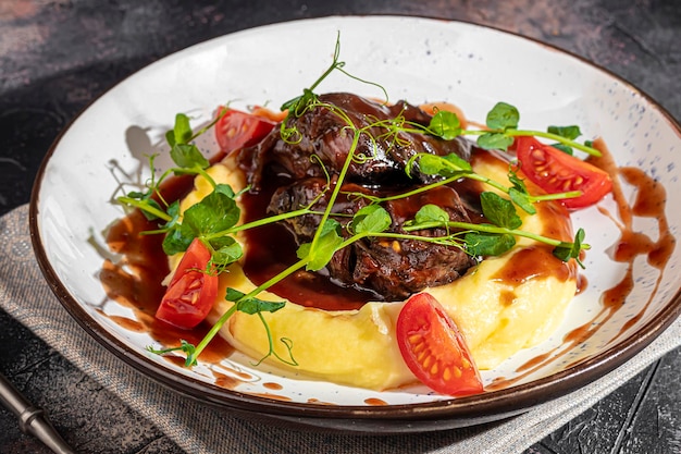 Purée de pommes de terre avec du bœuf dans une sauce sucrée et aigre décorée de tomates et de microgreens