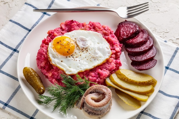 Purée de pommes de terre Labskaus avec l'œuf frit à la betterave