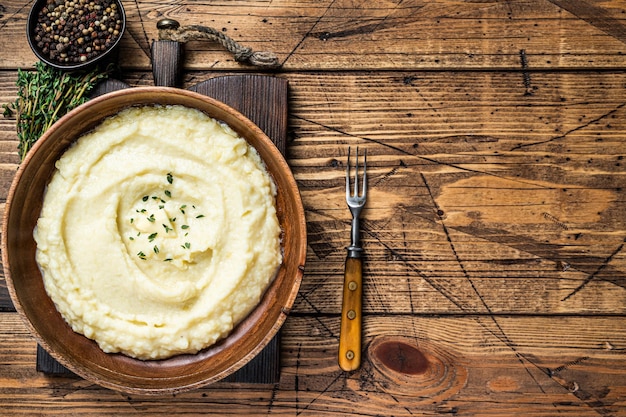 Purée de pommes de terre, purée bouillie dans une assiette en bois. Fond en bois. Vue de dessus. Espace de copie.