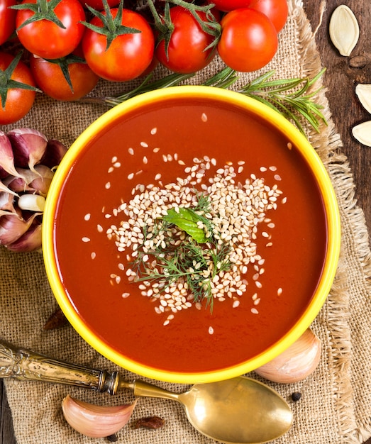 Purée de soupe aux tomates fraîches et légumes crus sur une table en bois avec espace copie