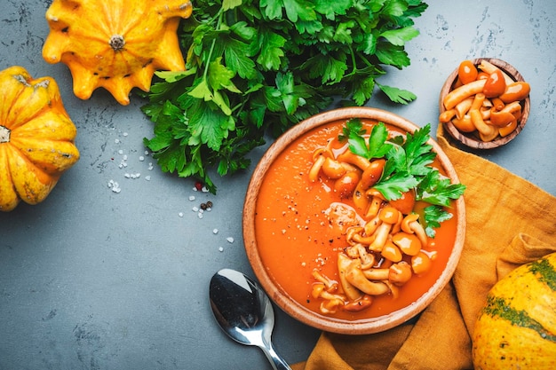 Purée de soupe de citrouille végétalienne aux champignons poivre et persil Hiver ou automne nourriture lente végétarienne saine Bol en céramique sur fond de table gris Vue de dessus