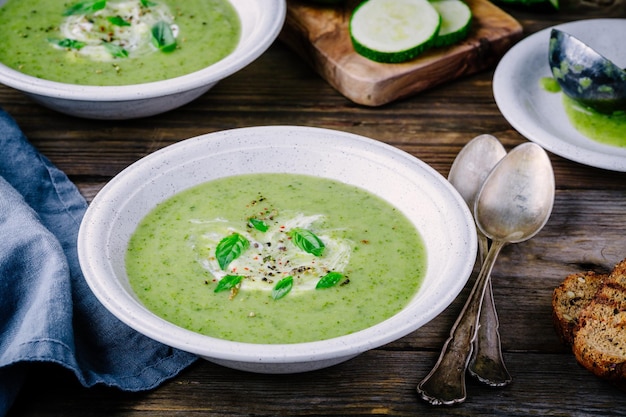 Purée de soupe à la crème de légumes verts aux courgettes et basilic sur fond de bois