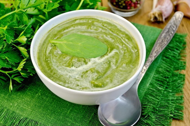 Purée verte dans un bol sur la planche avec des épinards