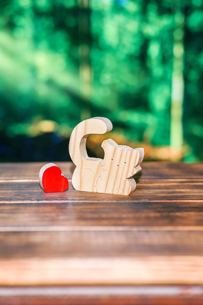 Puzzle en bois brouillé sous forme de chat fait main avec un coeur sur le fond d'une forêt brouillée