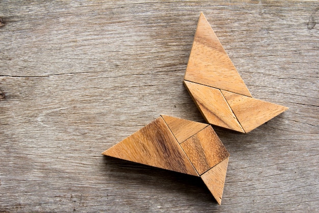 Puzzle de tangram en bois en vol fond de forme de papillon