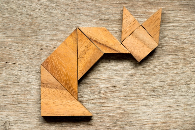 Photo puzzle de tangram en forme de chat assis sur fond de bois