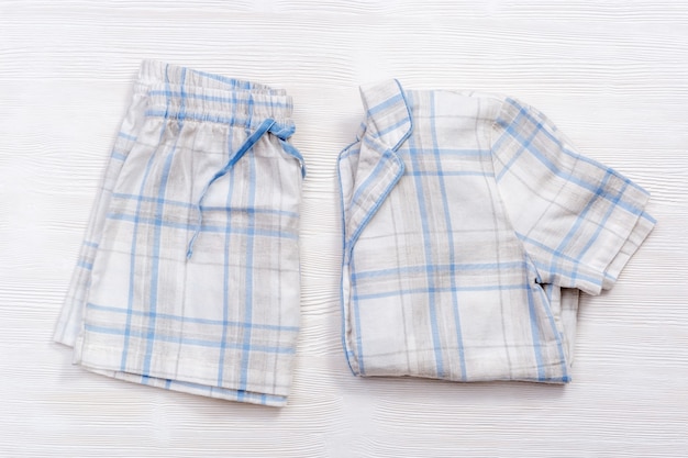 Pyjama plié blanc chaud à carreaux bleus ou à rayures sur bois blanc