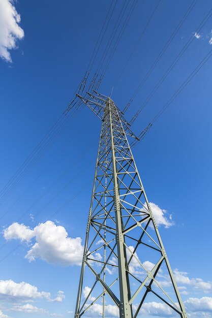 Pylône électrique sur la haute tension de l'industrie du ciel nuageux bleu