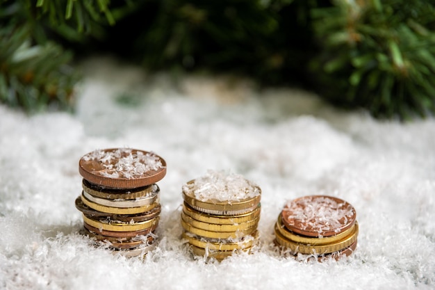 Une pyramide dorée de pièces de monnaie recouverte de neige sur fond de branches d'épinette verte. Notion de réussite.