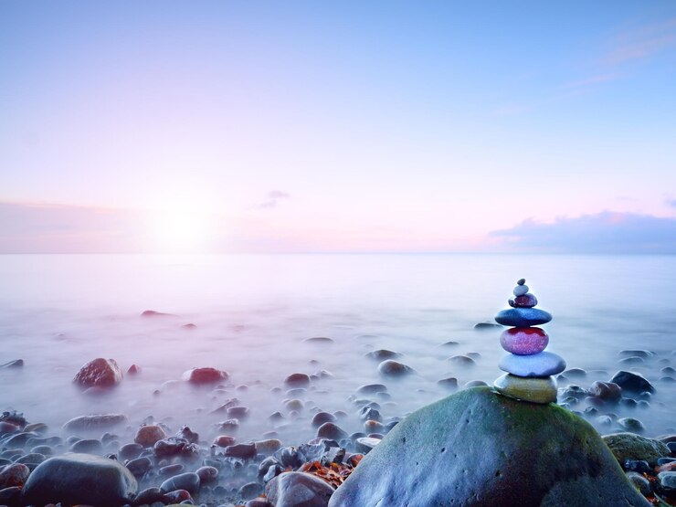 Photo pyramide de pierre équilibrée sur le rivage de l'eau bleue de l'océan ciel bleu dans le miroir de niveau d'eau