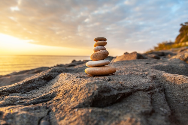 Pyramide de pierres au bord de la mer au coucher du soleil