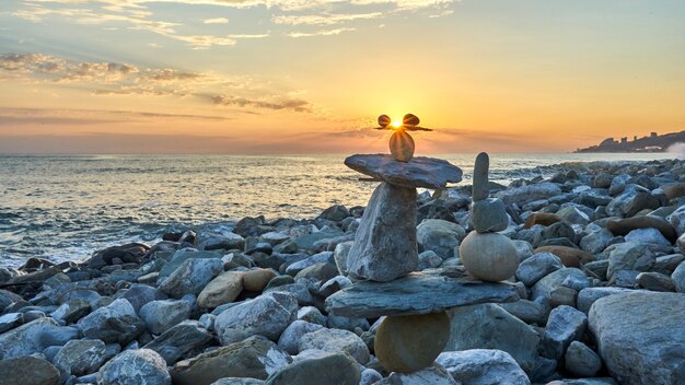 Pyramide des pierres isolées sur fond de coucher de soleil, bord de mer