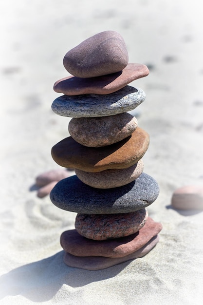 Pyramide de pierres sur une plage de sable Pierres d'équilibre zen au soleil