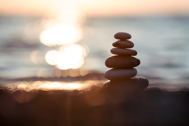 Photo pyramide de pierres pour la méditation allongée sur la côte de la mer au coucher du soleil