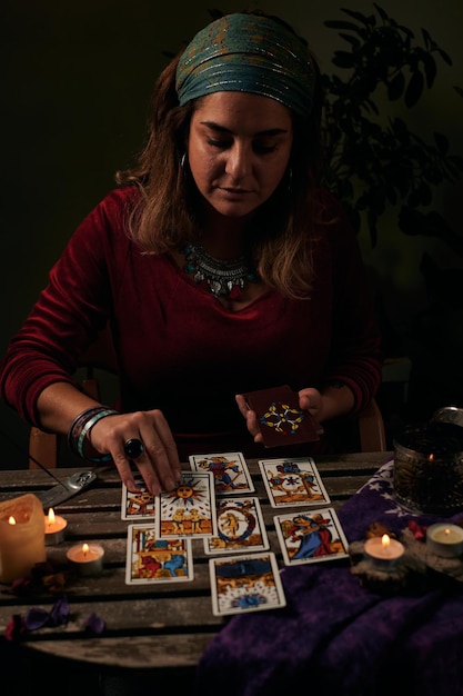 La pythonisse lit des cartes de tarot sur une table avec des bougies