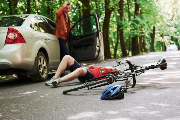 Qu'est-ce que j'ai fait. Victime sur l'asphalte. Location et accident de voiture de couleur argentée sur la route en forêt pendant la journée