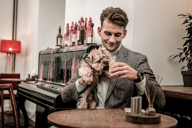 Qu'est-ce que l'on boit. Le petit terrier reniflant le café de ses propriétaires