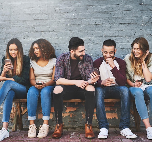 Qu'est-ce que la vie sans amis et sans wifi Photo d'un groupe de jeunes amis utilisant leur téléphone portable à l'extérieur