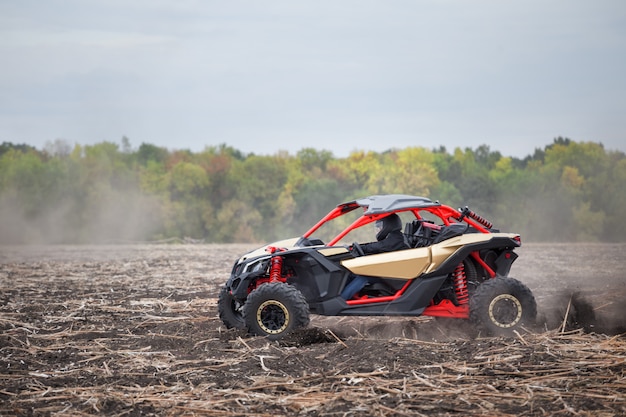 Quad rouge avec un conducteur dans un champ labouré