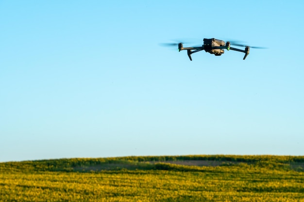 Un quadcopter moderne survole un champ de tournesols contre le coucher du soleil L'utilisation des technologies modernes dans le complexe agro-industriel Le drone aide l'agriculteur dans l'agro-industrie