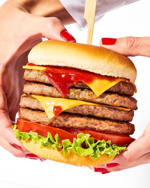 Photo quadruple steak burger avec cheddar et laitue tenu à deux mains