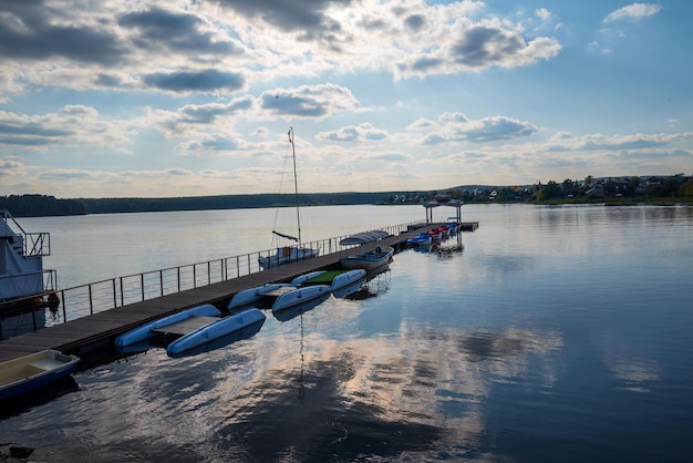 Photo un quai avec des bateaux sur le lac sur le fond d'un ciel au coucher du soleil avec des nuages