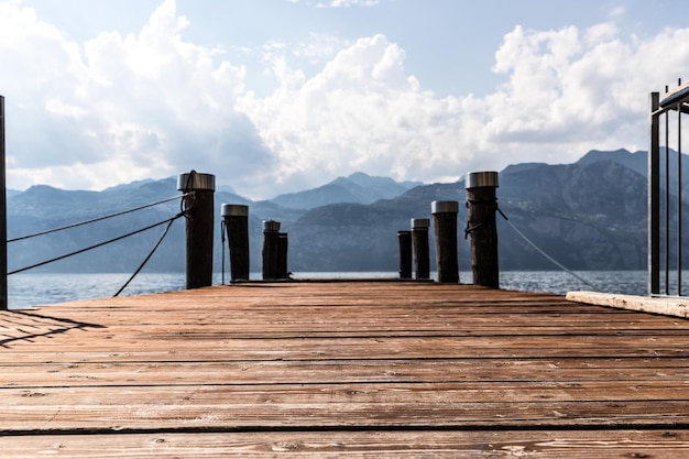 Quai en bois s'étendant sur les montagnes d'eau du lac bleu au lago di garda