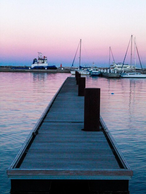 Un quai avec un ciel violet et des bateaux dans l'eau.