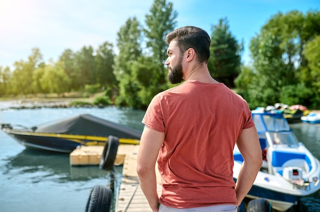 Sur un quai. Un homme aux cheveux noirs debout sur un quai près du bateau