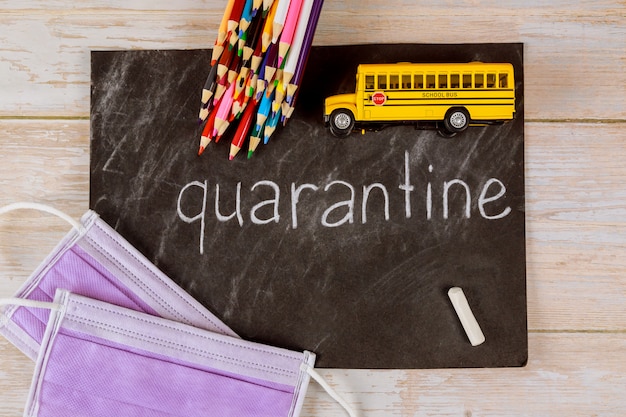 Quarantaine à l'école pour le concept de l'élève. Tableau noir, crayons et jouet de bus.