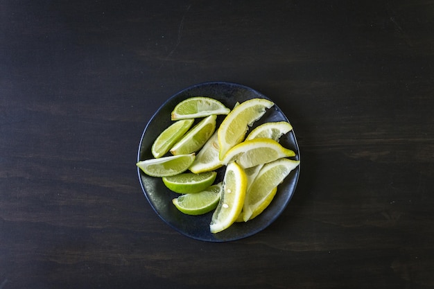 Quartiers de citron et de lime sur plaque noire sur fond noir.