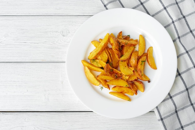 Quartiers de pommes de terre frites en plaque sur table en bois blanc