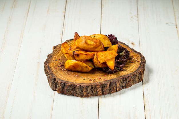 Quartiers de pommes de terre frites rustiques sur une planche de bois