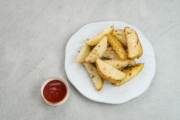 Quartiers de pommes de terre rôties au romarin et herbes servis avec sauce chili