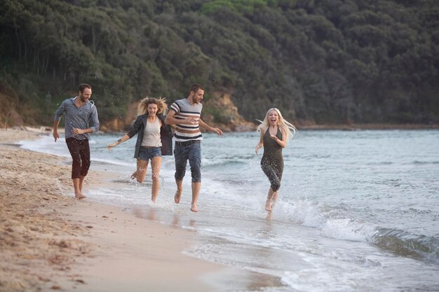 Quatre amis heureux courant à la plage