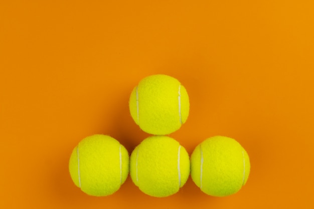 Photo quatre balles de tennis sur une surface orange