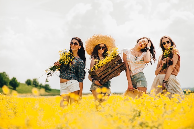 quatre belle fille hippie dans un champ de fleurs jaunes